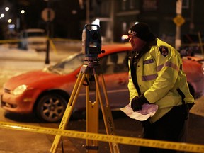 A Windsor police collision reconstruction officer studies the scene of a collision between a red Chrysler Neon and two pedestrians in the Walkerville area on Jan. 10, 2015. (Rick Dawes / The Windsor Star)