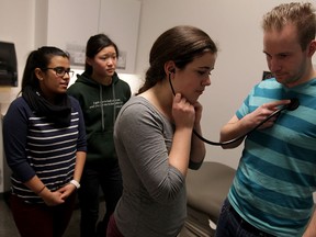 Local high school students Rufaida Ansari, left, Lily Xu and Nicole Fletcher receive a hands-on tour of Western University Schulich School of Medicine and Dentistry at the University of Windsor, from 2nd-year medical student Chris Langley, right, Tuesday February 3, 2015.  Langley demonstrated a typical cardio and respiratory examination for the touring students. (NICK BRANCACCIO/The Windsor Star)