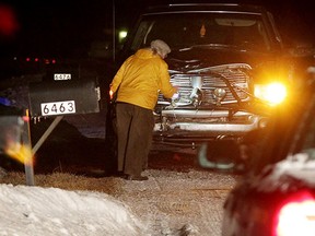 Coroner Dr. Marven Oxley checks the front grill of a vehicle following a fatal accident on Walker Road, south of South Talbot Road February 9, 2015. OPP were at the scene investigating and Walker Road was blocked in both directions. (NICK BRANCACCIO/The Windsor Star)