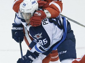 Detroit's Kyle Quincey, top, checks Winnipeg's Mathieu Perreault during the third period Saturday in Detroit. (AP Photo/Carlos Osorio)