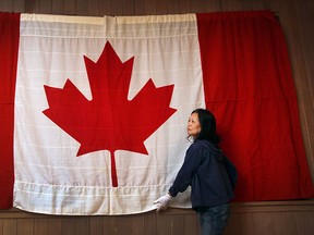 Elen Eng, a volunteer with Windsor's Community Museum prepares one of the original 1965 first-day-flags Canadian flags on display on February 10, 2015.  (JASON KRYK/The Windsor Star)