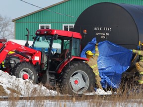 Lakeshore firefighters use a tarp to cover the immediate area as Essex-Windsor EMS paramedics and OPP investigate a fatal accident involving a tractor shunting railcars at Elmstead Road and CP tracks Friday Feb. 27, 2015. (NICK BRANCACCIO/The Windsor Star)