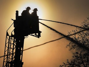 Windsor firefighters battle a house fire on Wednesday, Feb. 18, 2015, in the 700 block of Windsor Ave. Two firemen in an aerial bucket are silhouetted as they attack the fire.  (DAN JANISSE/The Windsor Star)