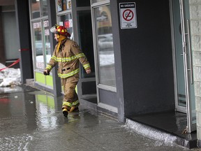 Windsor Fire and Rescue work to shut off a significant water leak at 540 Ouellette Ave., Sunday, Feb. 22, 2015.  Water could be seen streaming out of the lobby onto the street, as well as streaming down the walls of the Manchester Pub next door.  (DAX MELMER/The Windsor Star)