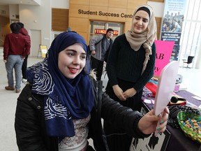 Rehab El-hage talks to Diana Trojansek (left) while she tries on a hijab during a hijab awareness event at the University of Windsor in Windsor on Wednesday, February 4, 2015. Students at the university were given the chance to try on a hijab.  (TYLER BROWNBRIDGE/The Windsor Star)