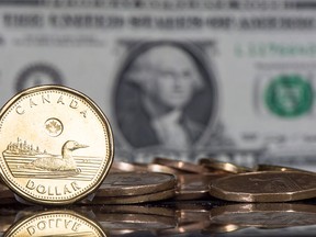 The Canadian dollar coin, the Loonie, is displayed next to the US dollar Friday, January 30, 2015 in Montreal. THE CANADIAN PRESS/Paul Chiasson