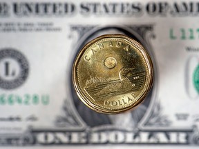 The Canadian dollar coin, the Loonie, is displayed over the US dollar. (PAUL CHIASSON/The Canadian Press)