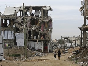 Palestinian children walk between the rubble of buildings which were destroyed during the summer 2014 Israel-Hamas war, in the Shijaiyah neighborhood in Gaza City, in the northern Gaza Strip, Monday, Feb. 23, 2015. (AP Photo/Adel Hana)