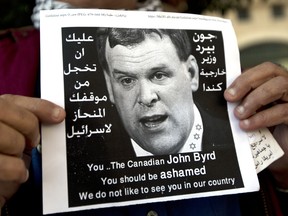 A Palestinian protester holds a poster with a photo of Canadian Foreign Minister John Baird that reads in Arabic, "You should be ashamed of your biased position towards Israel," during Baird's meeting with Palestinian Foreign Minister Riad Malki, in front of the Palestinian foreign ministry in the West Bank city of Ramallah, Sunday, Jan. 18, 2015. Dozens of Palestinian protesters have hurled eggs and shoes at the convoy of the visiting Canadian foreign minister. President Mahmoud Abbas' Fatah party earlier called for a boycott of Baird because of Canada's perceived pro-Israel stance. (AP Photo/Nasser Nasser)