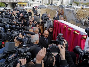 Mufid Hassayneh, Palestinian minister of public works, center, and Mohammed Abu Haloub of Qatar Charity, unseen, speaks to the media during a cornerstone ceremony for rebuilding Zafer 4 Tower in Gaza, in the northern Gaza Strip, Wednesday, Feb. 18, 2015. Palestinian officials have laid the cornerstone for the rebuilding of a residential high-rise flattened in last summer's war between the Islamic militant group Hamas and Israel. Wednesday's ceremony by Gaza's public works minister was a symbolic move to boost the spirits of the nearly 500 residents of Zafer 4 Tower, which was hit by two bombs from the air during fighting in August. (AP Photo/Adel Hana)