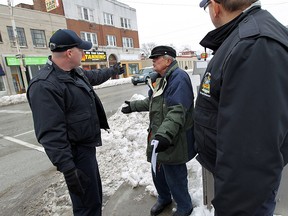 Bylaw officer Bill Tetler (left) and Bart Pogorzelski (right) talk to the parking lot owner Tom Alexopoulos during a crackdown on those who have not cleared their sidewalks in Windsor on Wednesday, February 4, 2015.  (TYLER BROWNBRIDGE/The Windsor Star)