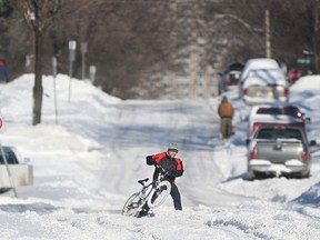 A man struggles commuting with his bike after a winter storm dumped over 30cm of snow in the Windsor region, Monday, Feb. 2, 2015. (DAX MELMER/The Windsor Star)