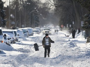 A man walks down the middle of the street with a snow shovel as residents on Langlois Ave. try to clear away the snow after a winter storm dumped over 30cm of snow in the Windsor region, Monday, Feb. 2, 2015.  (DAX MELMER/The Windsor Star)