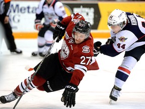 Windsor's Luke Kirwan, right, trips Guelph's Garrett McFadden during OHL action in Guelph Monday, Feb. 16, 2015. Kirwan was penalized on the play and the Storm went on to win the game 5-4 in overtime. (Photo courtesy of Tony Saxon, Guelph Mercury)