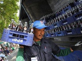 FILE - In this Oct. 22, 2012 photo, a worker carries a crate of Pepsi for delivery in Bangkok, Thailand. When beverage giants Coca-Cola and PepsiCo turned in their quarterly results last week, both blamed the dollar for cutting into their profits because, like most U.S. corporations, they rely on overseas sales.  (AP Photo/Sakchai Lalit, File)