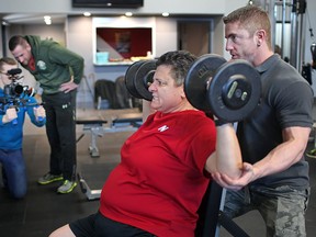 Anne Campeau, a participant on the reality television show Radical Body Transformation, works out with trainer Ken Dennison at Onyx Fitness Solutions on Monday in Essex. Filming them were Murray Urquhart and Adam Pedersen, left, from Radical Body Transformation. (DAX MELMER / The Windsor Star)