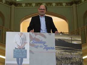 Black Moss publisher Marty Gervais poses with a poster of three books his company is about to release. (JASON KRYK / The Windsor Star)