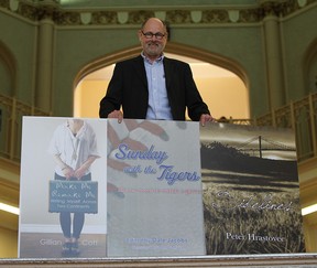 Black Moss publisher Marty Gervais poses with a poster of three books his company is about to release. (JASON KRYK / The Windsor Star)