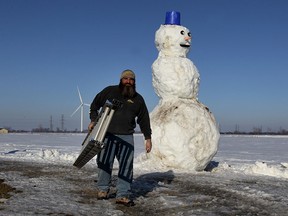 Andre Lariviere had to adjust his massive snowman as warmer temperatures melted away a portion of the Woodslee attraction Monday March 9, 2015.   Plans are to disassemble the snowman later this week.  (NICK BRANCACCIO/The Windsor Star)