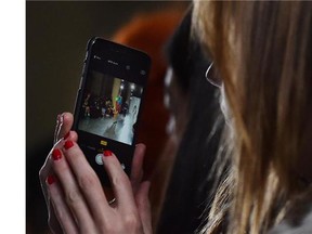 A member of the crowd uses a smartphone to photograph a model on the catwalk presenting a creation from the Marques' Almeida collection during the 2015 Autumn / Winter London Fashion Week in London on February 24, 2015. (Postmedia News files)