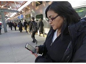 Marilu Rodriguez checks a news website on her smartphone before boarding a train home at the end of her work week in Chicago on March 13, 2015.  (Associated Press files)