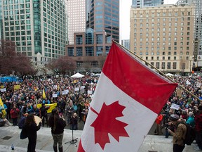 A demonstrator flies a Canadian flag upside down during a protest on a national day of action against Bill C-51, the government's proposed anti-terrorism legislation, outside the Vancouver Art Gallery in downtown Vancouver, Saturday, March 14, 2015. THE CANADIAN PRESS/Jonathan Hayward