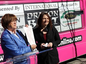 Penny Williams is joined by Tania Radu (right) as they place the first ribbon sticker on a pink bus during the launch of a new breast cancer awareness bus at the bus terminal in Windsor on Thursday, March 12, 2015. The Windsor Transit bus will help raise money for breast cancer. (TYLER BROWNBRIDGE/The Windsor Star)