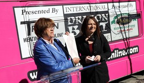 Penny Williams is joined by Tania Radu (right) as they place the first ribbon sticker on a pink bus during the launch of a new breast cancer awareness bus at the bus terminal in Windsor on Thursday, March 12, 2015. The Windsor Transit bus will help raise money for breast cancer. (TYLER BROWNBRIDGE/The Windsor Star)