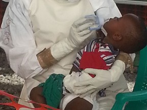 An aid worker feeds a patient at the Kono Ebola treatment centre in Sierra Leone. (Courtesy of Nikola Latinovic)