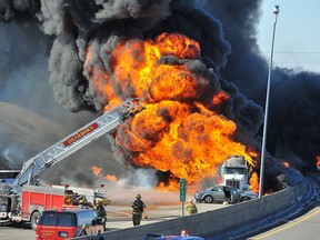 Dearborn, Mich., firefighters watch as a tanker truck, and at least one car, right, burn shutting down a stretch Interstate 94, Wednesday, March 11, 2015, Dearborn, Mich. Michigan State Police Lt. Michael Shaw says there were no reports of injuries. He says the truck was believed to have been hauling petroleum. (AP Photo/Detroit News, Daniel Mears)