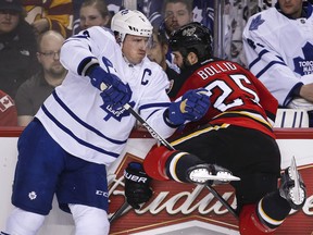 Toronto's Dion Phaneuf, left, checks Calgary's Brandon Bollig during the second period in Calgary Friday. (THE CANADIAN PRESS/Jeff McIntosh)