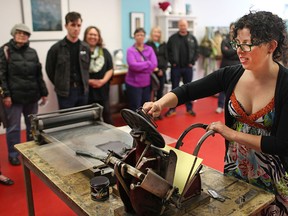 Jodi Green, owner of the Levigator Press - Print Studio and Gallery, gives a printing demonstration on a platen press during the grand opening of the printing studio in Walkerville, Saturday, March 14, 2014.  (DAX MELMER/The Windsor Star)