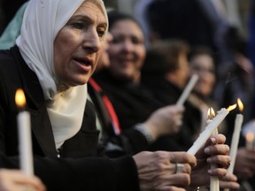 An Egyptian Muslim woman lights candles during a vigil for Christians who were killed in Libya, at St. Mark's Cathedral in Cairo, Egypt, Tuesday, Feb. 17, 2015. An Islamic State video released on 15 February claimed to show the extremist group beheading 21 Egyptian Christians abducted in Libya more than a month ago. The Egyptian army responded on Feb. 16 by an airstrike against the militants targeting bases and weapons storage facilities in Libya. (AP Photo/Amr Nabil)