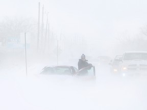 A motorist almost disappears in the haze on a snowy County Road 42 on Feb. 14, 2015. (Dax Melmer / The Windsor Star)
