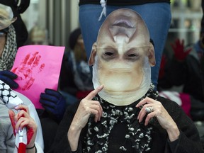A pro-Palestine demonstrator, led by Code Pink, wears a Israeli Prime Minister Benjamin Netanyahu mask upside down as she joins a protest in front of the Washington Convention Center where the 2015 American Israel Public Affairs Committee (AIPAC) Policy Conference is being held, in Washington, Sunday, March 1, 2015. (AP Photo/Cliff Owen)