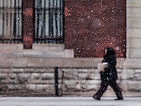 A woman walks along University Ave. East in front of the former Armouries building during a brief snow fall, Friday, March 27, 2015.  (DAX MELMER/The Windsor Star)