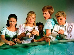 Chairmian Carr as Liesl, left, Heather Menzies as Louisa, Julie Andrews as Maria, and Nicholas Hammond as Friedrich, in a scene with puppets from The Sound of Music.