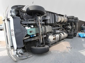 Tow truck operators work to right a semi truck that tipped over in the roundabout at Highway 3 and Howard Ave. on Wednesday, April 22, 2015, in Windsor. The eastbound lanes were shut down for several hours as the contents of the truck were transferred. No injuries were reported. (DAN JANISSE/The Windsor Star)