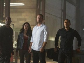 This photo provided by Universal Pictures shows, from left, Tyrese Gibson as Roman, Michelle Rodriguez as Letty, Paul Walker as Brian, and Chris Ludacris as Tej, in a scene from "Furious 7." (AP Photo/Universal Pictures, Scott Garfield)