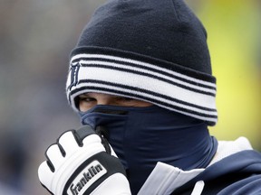 Detroit Tigers relief pitcher Joba Chamberlain wears gloves, a hat and a facemask, to keep warm in the dugout before the first inning against the New York Yankees, Thursday in Detroit. (AP Photo/Carlos Osorio)