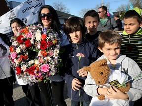 Widow Veronica Cardoso, centre, holds a wreath with sons, Mateo and Maui, right, and other family members during National Day of Mourning event at St. Augustine/St. Aiden's Church hall on Wyandotte Street East. Several hundred mourners and injured workers attended the church and marched in procession to Coventry Gardens for laying of wreaths at Workers Monument. Veronica's husband Claudio Cardoso was killed while working in January 2009. (NICK BRANCACCIO/The Windsor Star)