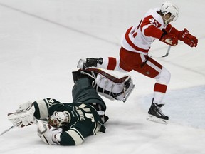Minnesota Wild goalie Devan Dubnyk, left, dives on a point-blank shot by Detroit Red Wings center Darren Helm (43) as Helm leaps to avoid him during the first period of an NHL hockey game in St. Paul, Minn., Saturday, April 4, 2015. (AP Photo/Ann Heisenfelt)