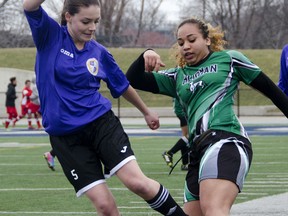 Assumption's Ella Hooper, left, battles for the ball during a 3-2 loss against Herman in high school girls soccer Tuesday at Alumni Field. (GABRIELLE SMITH/Special to The Windsor Star)