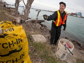 Mike Stadler, from the H.M.C.S Hunter, picks up garbage along the Detroit River during Crime Stoppers' Take Back Our Neighbourhood community clean up event, Saturday, April 25, 2015.  (DAX MELMER/The Windsor Star)