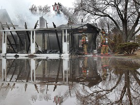 A woman surveys the damage to a house at a lakefront home at the Westchester Beach in Harrow, Ont. on Wednesday, April 8, 2015. (DAN JANISSE/The Windsor Star)
