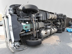 Tow truck operators work to right a semi truck that tipped over in the roundabout at Highway 3 and Howard Ave. on Wednesday, April 22, 2015, in Windsor, ON. The eastbound lanes were shut down for several hours as the contents of the truck were transferred. No injuries were reported. (DAN JANISSE/The Windsor Star)