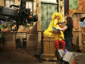 Michelle Hickey, a Muppet wrangler adjusts a book for Big Bird, voiced by Carroll Spinney, so he can read to Connor Scott during a taping of Sesame Street in New York. Spinney drops his fine-feathered obscurity (and emerges from his garbage-can fortress as Oscar the Grouch) for an enchanting film portrait, "I Am Big Bird: The Caroll Spinney Story," which celebrates the "Sesame Street" puppet master who, at age 81, continues to breathe life into a pair of the world's best-loved personalities. (AP Photo/Mark Lennihan, File)