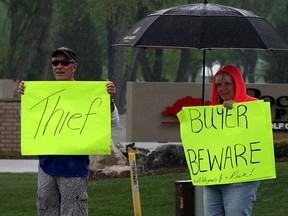 Deb Robert, right, a resident at Rochester Place Resort Inc. protests on Old Tecumseh Road at the Ruscom River, May 16, 2015. About a dozen residents and their supporters held placards in the rain for several hours to get their message across to visitors and motorists passing by. (NICK BRANCACCIO/The Windsor Star)