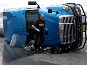 OPP investigate on Highway 3 after the driver of a tractor-trailer rig escaped after overturning Sunday. Driver Richard Rowe was hauling 80,000 lbs. of grape concentrate. (NICK BRANCACCIO/The Windsor Star)