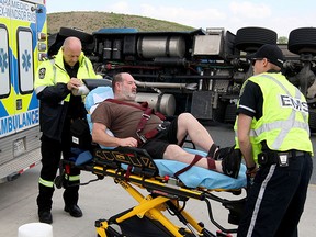 Truck driver Richard Rowe is placed on a stretcher after escaping from his tractor-trailer rig which overturned on Highway 3 roundabout at Howard Avenue Sunday.  Rowe was hauling 80,000 lbs. of grape concentrate and was assisted by Essex-Windsor EMS paramedics.  (NICK BRANCACCIO/The Windsor Star)